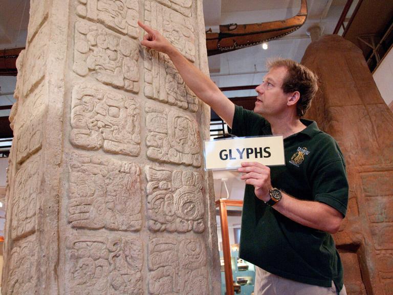 A man in front of a column of hieroglyphics