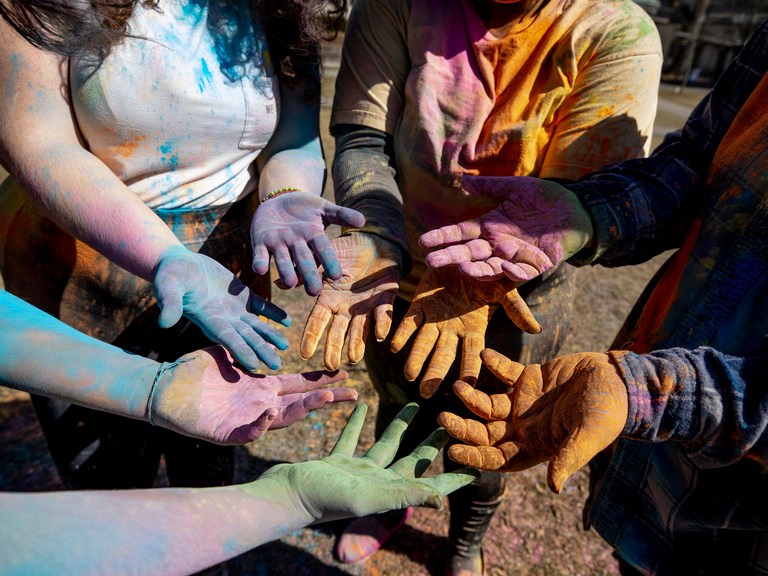 sets of hands covered in colorful dust.