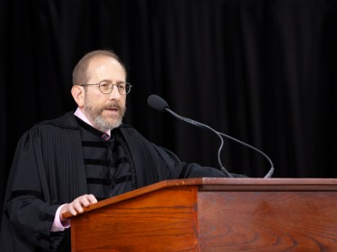 Aland Garber standing at a podium speaking.