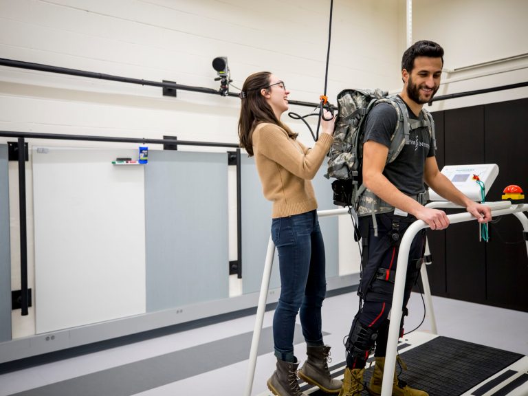 A student setting up a robot rig on the back of another student.