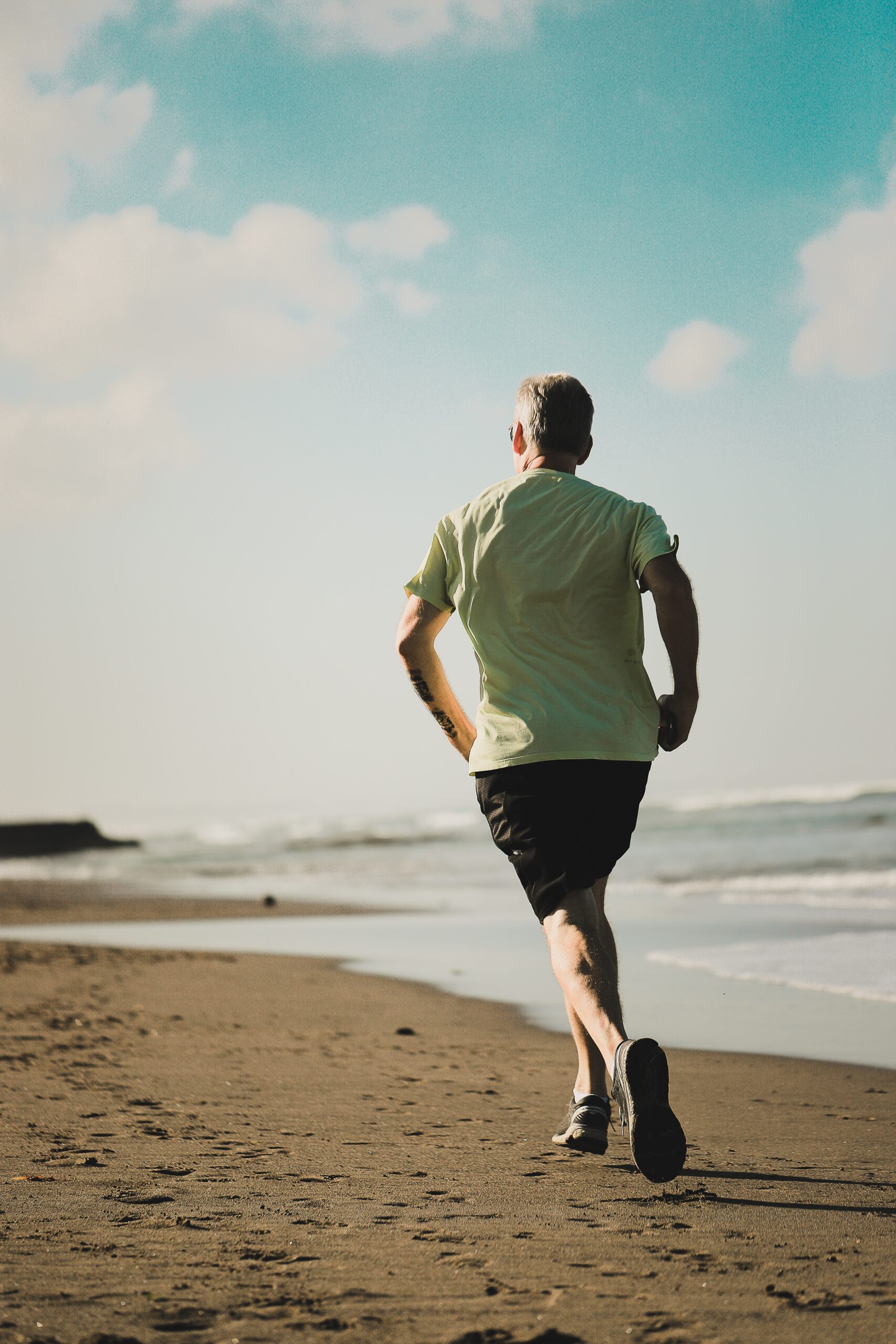 An older man running on a beach