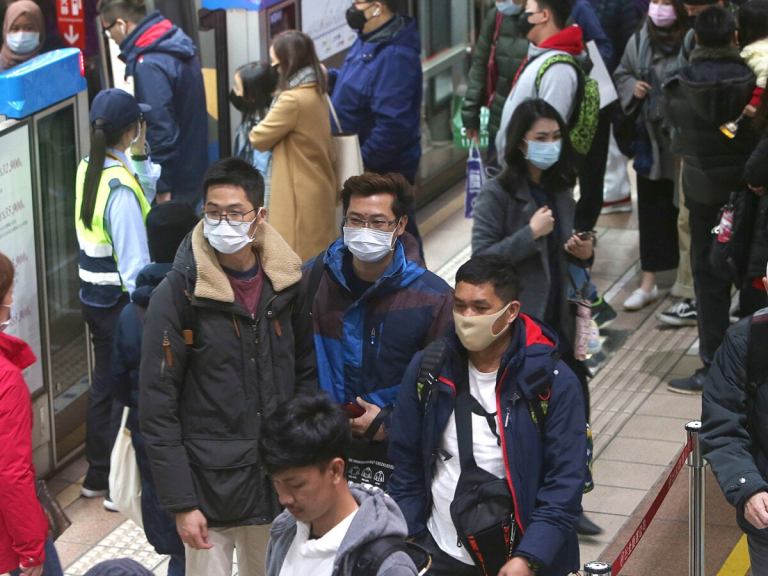 People getting off a train wearing masks
