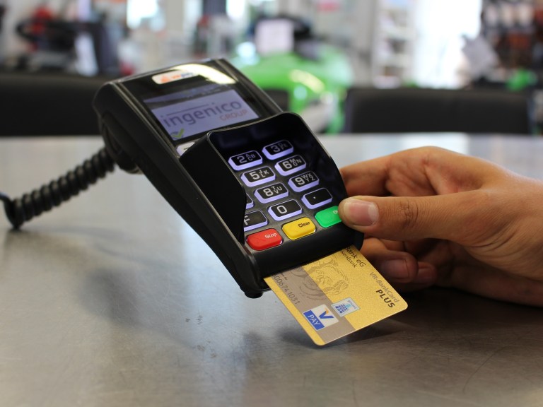 A person with their debit card in a card reader