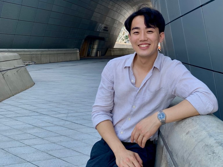 A young man leads against a concrete wall structure outside a tunnel