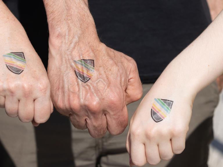 Hands with rainbow shields on them
