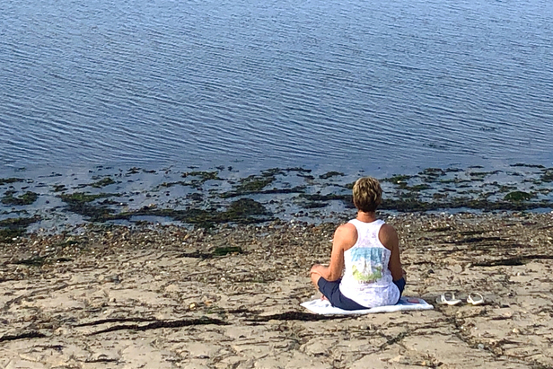 A person sitting on a beach meditating