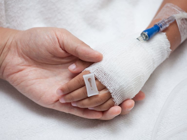 A person holding a sick child's hand