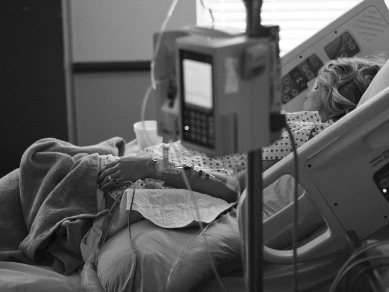 Black and white image of a woman laying in a hospital bed