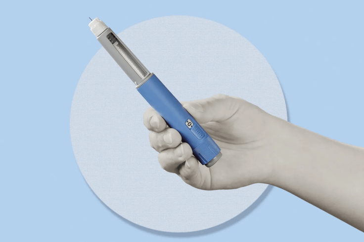 A graphic that includes a hand holding an injectable weight-loss drug