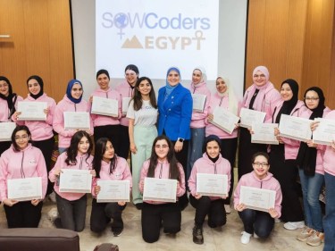 Graduates in the Egypt chapter of the Society of Women Coders wearing pink stand together holding certificates