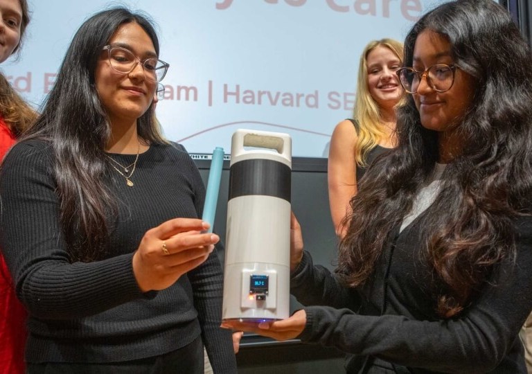 A group of students hold up a thermos-shaped device meant to keep medications cold.