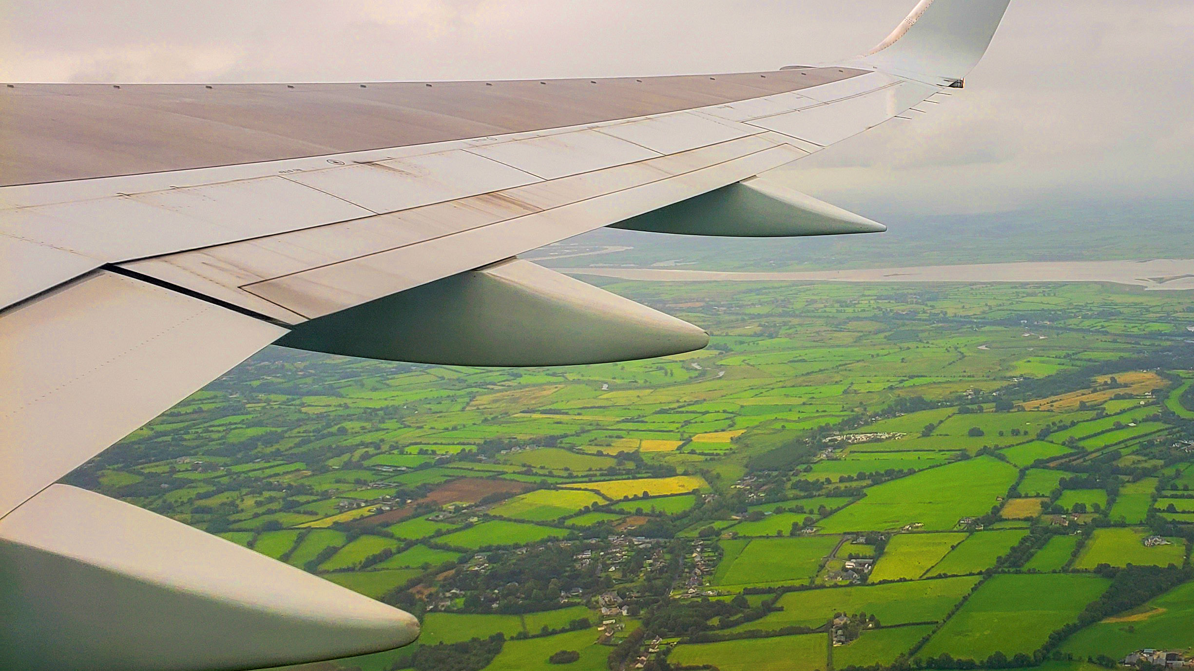 A plane flying over green land